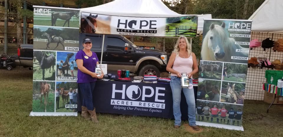 HOPE Acres Rescue booth with volunteers posed in front of it.