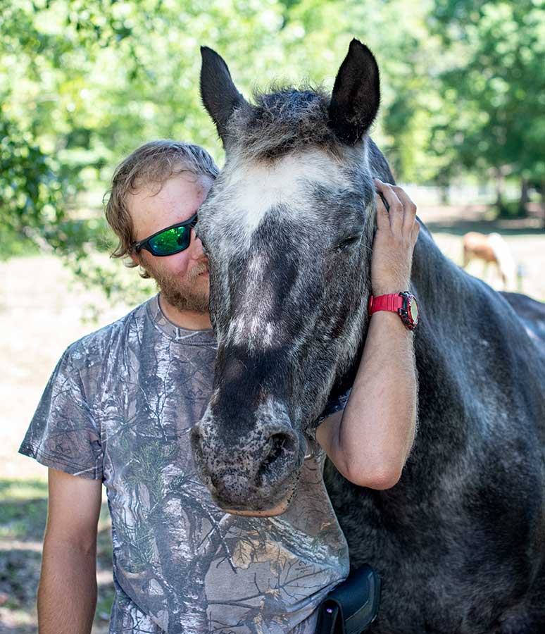 Ashleigh, an appaloosa mare, getting a hug from volunteer Jeffrey.